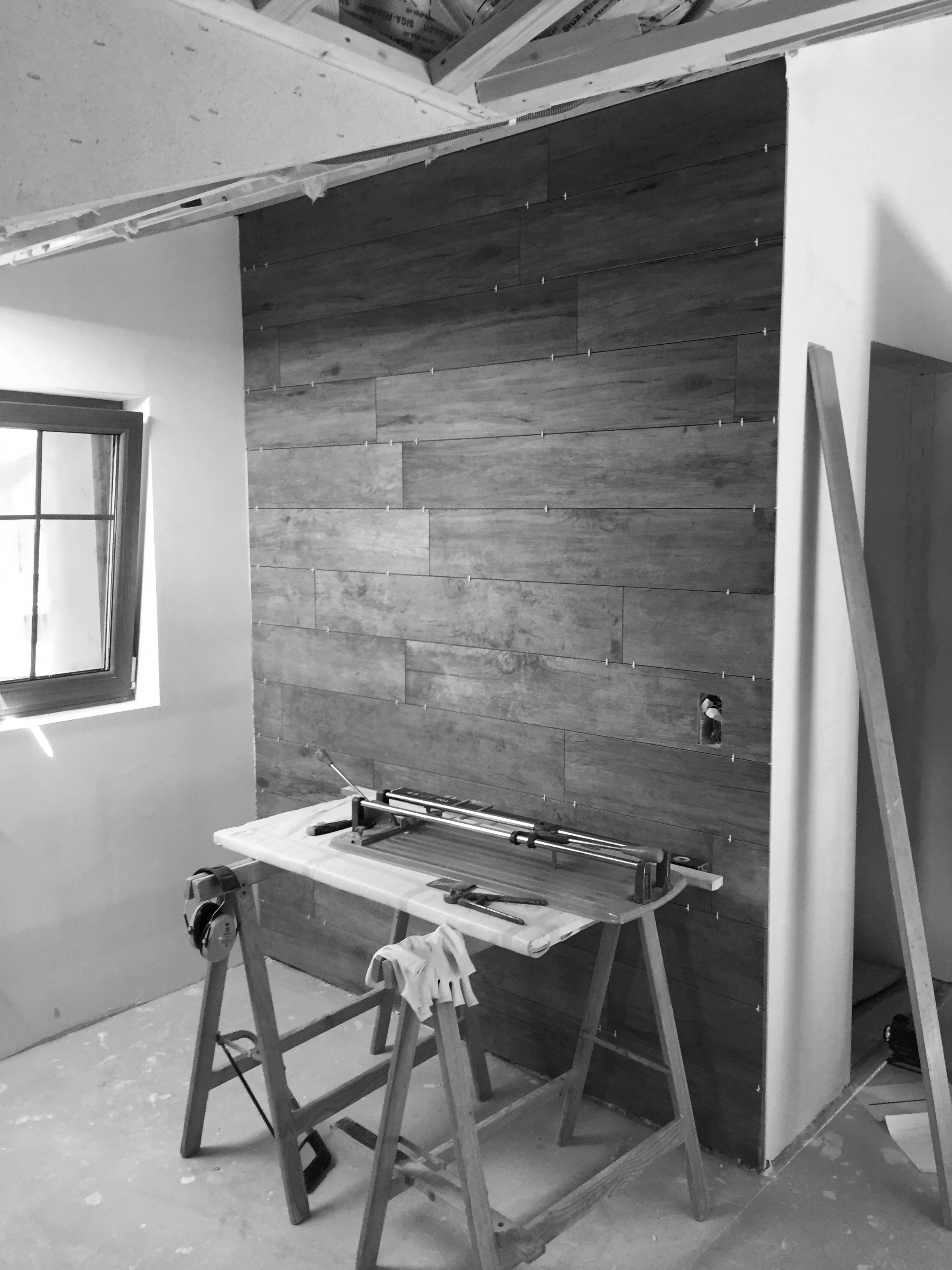 A partially finished interior space with a wooden accent wall, a workbench with tools, and a window providing natural light.