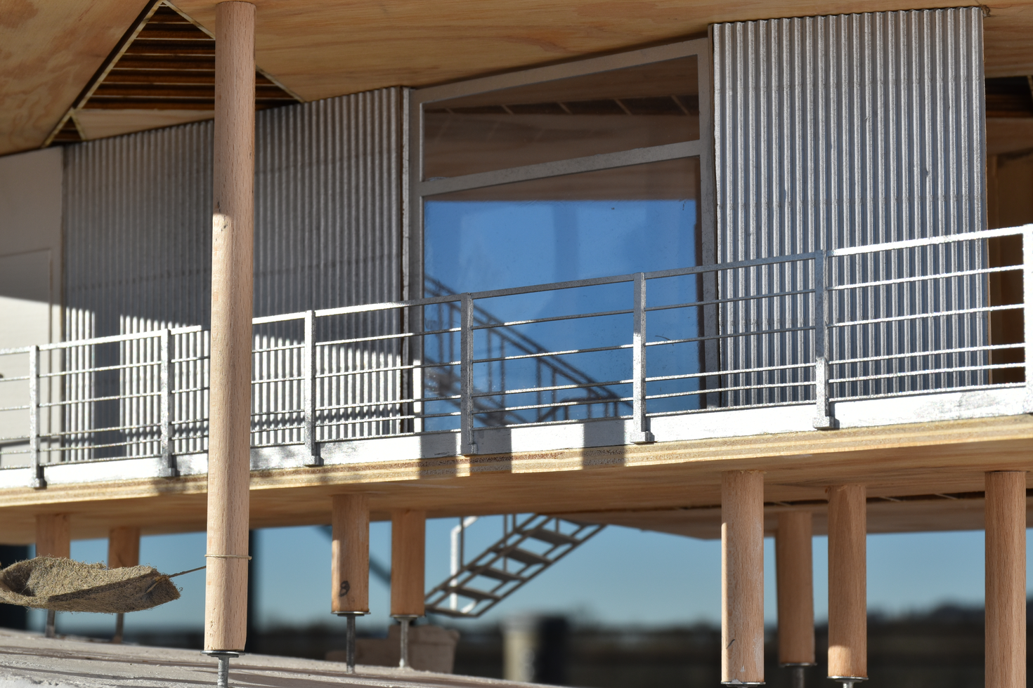高跷上的现代住宅房屋的建筑规模模型，带有木材和金属壁板，展示了具有高架居住空间的现代设计。